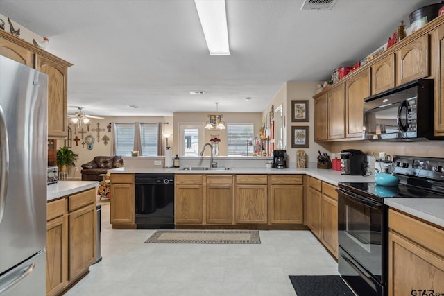 kitchen with a sink, a peninsula, black appliances, and light countertops
