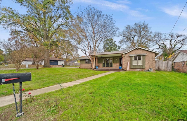 ranch-style home featuring covered porch and a front yard