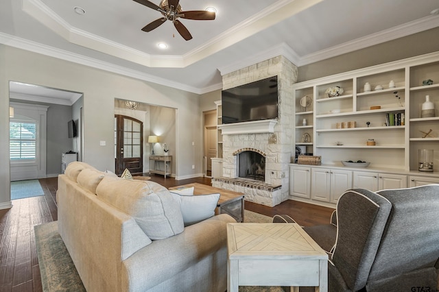 living room featuring ceiling fan, a stone fireplace, dark hardwood / wood-style flooring, and crown molding