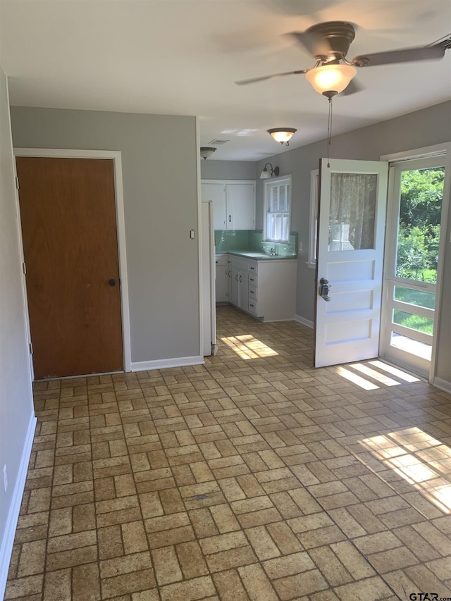 2326 Pleasant Dr, Tyler, TX 75701 - kitchen with white cabinetry, ceiling fan, brick patterned floors, light countertops, and freestanding refrigerator