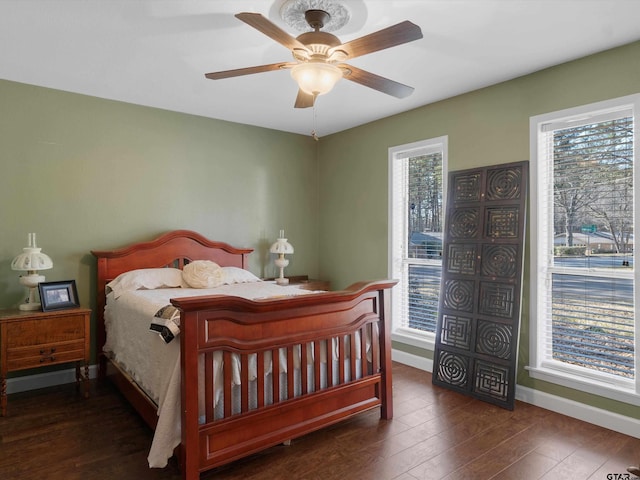 bedroom featuring multiple windows, dark hardwood / wood-style floors, and ceiling fan