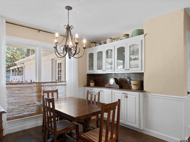 dining area with dark wood-type flooring and a notable chandelier