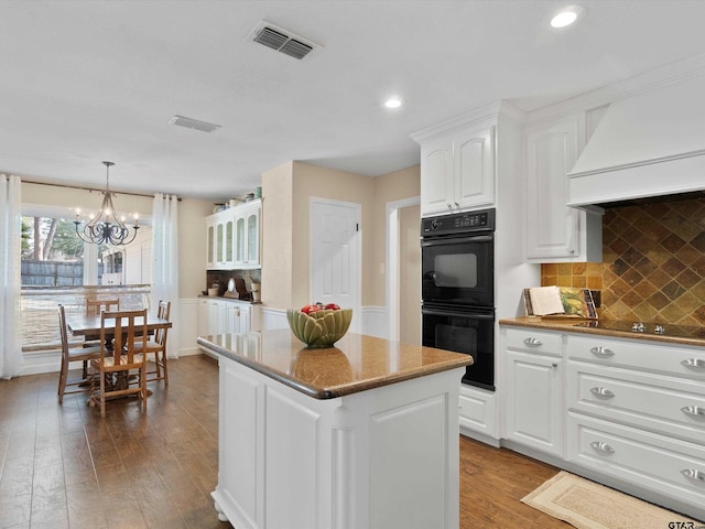 kitchen with pendant lighting, white cabinetry, hardwood / wood-style floors, a center island, and black appliances