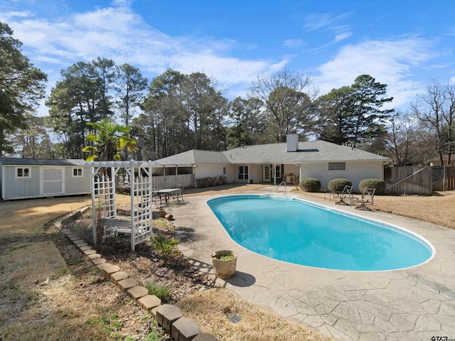 view of swimming pool with a storage unit, a pergola, and a patio