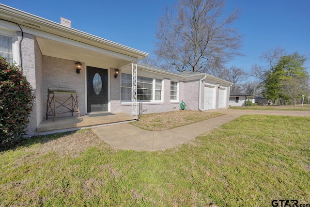 view of front of home with a garage, concrete driveway, a chimney, a front lawn, and brick siding