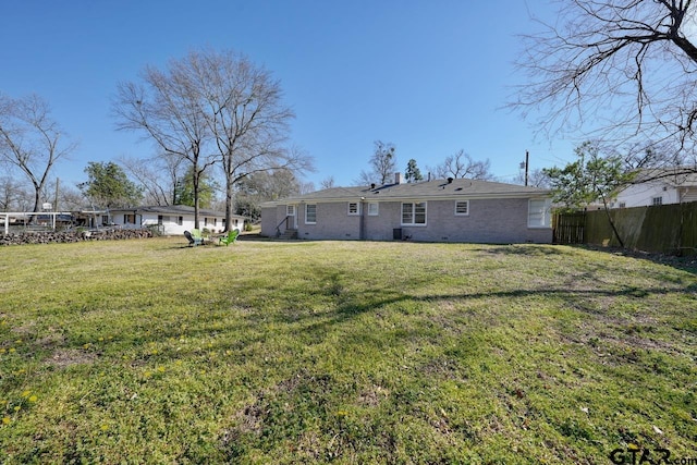 rear view of property with a yard, brick siding, and fence