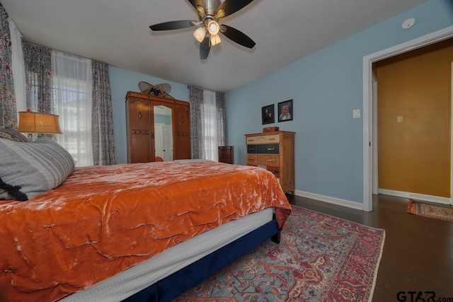 bedroom featuring a ceiling fan, baseboards, and wood finished floors