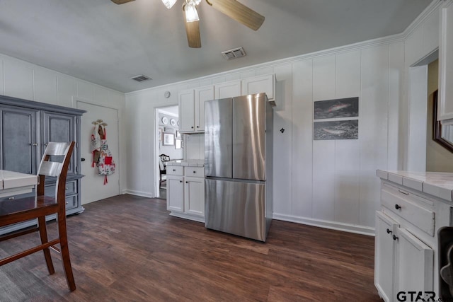 kitchen with visible vents, white cabinets, dark wood-style flooring, and freestanding refrigerator