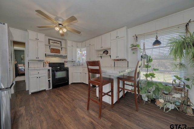 kitchen with open shelves, under cabinet range hood, freestanding refrigerator, and black electric range oven