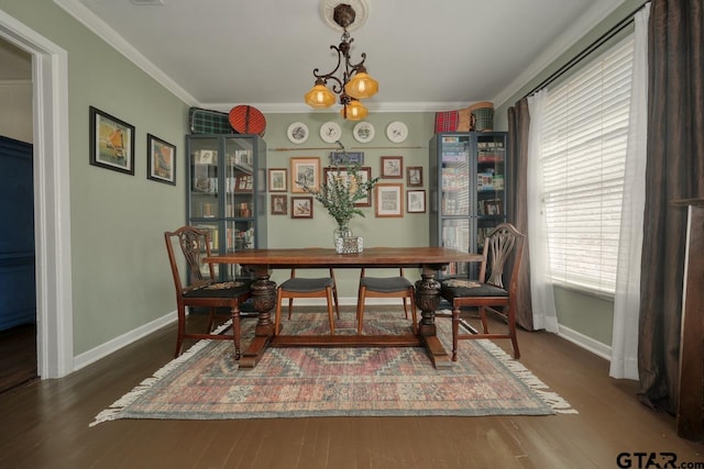 dining area featuring an inviting chandelier, baseboards, crown molding, and wood finished floors