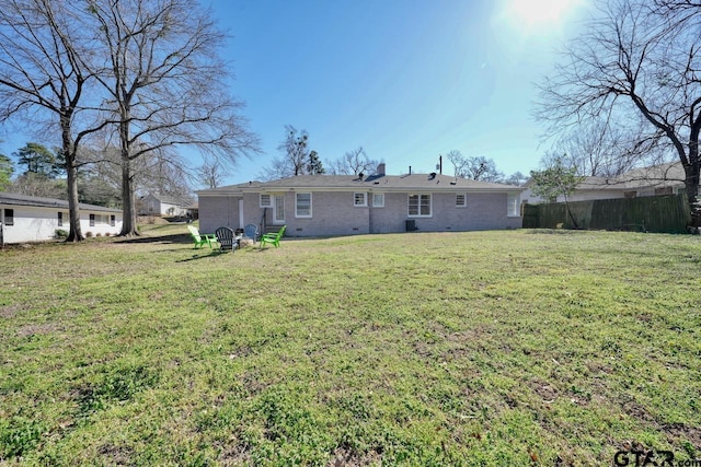 back of property with crawl space, brick siding, fence, and a yard