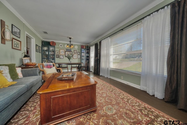 living area featuring baseboards, wood finished floors, visible vents, and crown molding