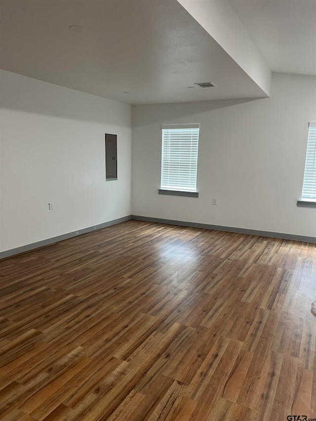 spare room with electric panel and hardwood / wood-style flooring