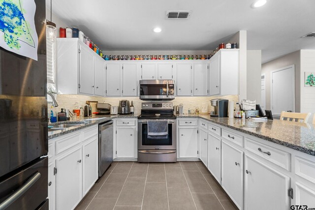 kitchen with backsplash, stone counters, white cabinetry, and stainless steel appliances