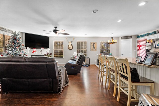 living room featuring ceiling fan with notable chandelier, a healthy amount of sunlight, and dark hardwood / wood-style flooring