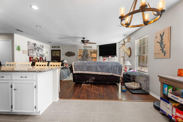 bedroom with ceiling fan with notable chandelier and light hardwood / wood-style flooring