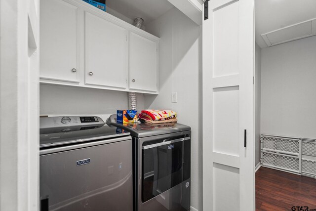 laundry area with washer and clothes dryer, dark hardwood / wood-style floors, a barn door, and cabinets