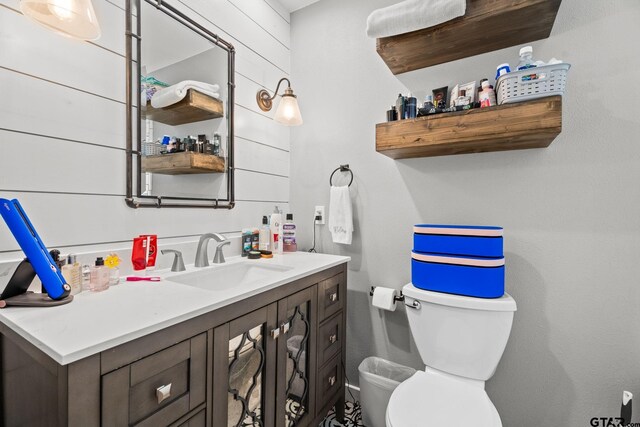 bathroom with wooden walls, vanity, and toilet