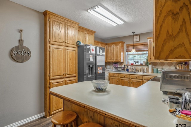 119 Vz County Road 4833, Chandler, TX 75758 - kitchen with a kitchen bar, stainless steel fridge, backsplash, a sink, and a peninsula