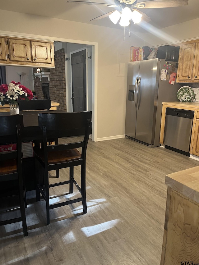 dining room featuring baseboards, ceiling fan, and light wood-style floors
