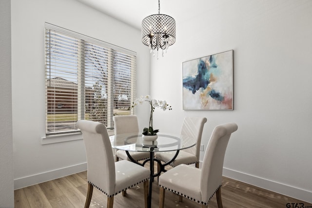 dining room with baseboards, wood finished floors, and a notable chandelier