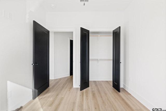 unfurnished bedroom with light wood-type flooring, baseboards, and a closet
