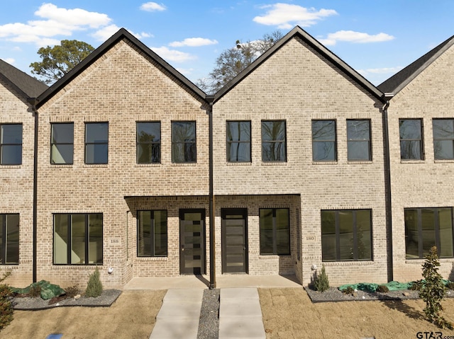 view of front facade with brick siding and a patio