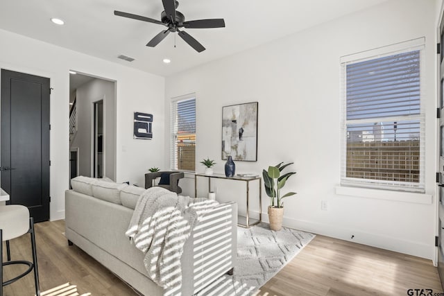living area with a ceiling fan, visible vents, a healthy amount of sunlight, and wood finished floors