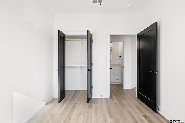 unfurnished bedroom with light wood-type flooring, baseboards, visible vents, and a closet
