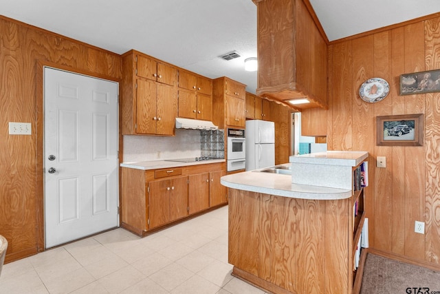 kitchen with decorative backsplash, kitchen peninsula, wooden walls, and white appliances