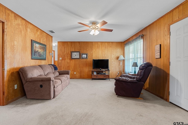 carpeted living room with ceiling fan and wood walls