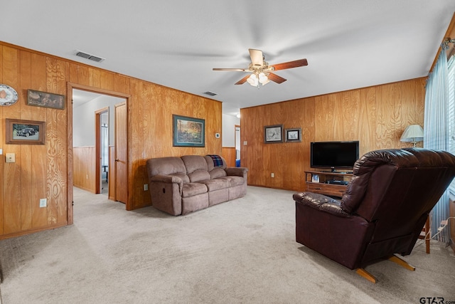 carpeted living room featuring ceiling fan and wood walls