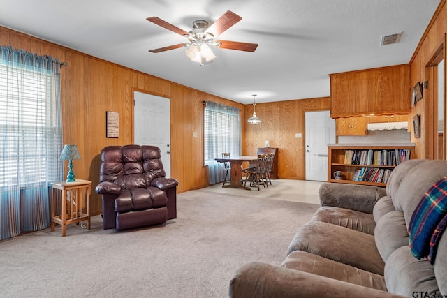 living room featuring ceiling fan, light carpet, radiator heating unit, and wooden walls