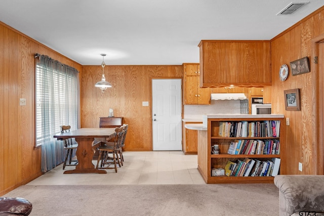 kitchen with wood walls, hanging light fixtures, light tile patterned floors, and kitchen peninsula