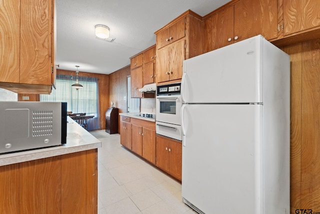 kitchen featuring decorative light fixtures, white appliances, and a textured ceiling