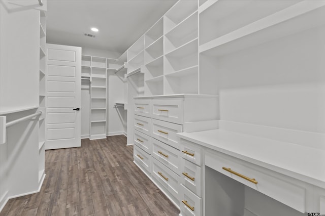 walk in closet with dark hardwood / wood-style floors and built in desk