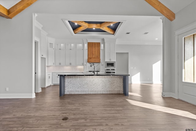 kitchen with built in microwave, stainless steel oven, white cabinets, and beam ceiling