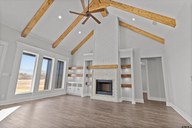 unfurnished living room featuring built in features, a fireplace, high vaulted ceiling, beamed ceiling, and ceiling fan