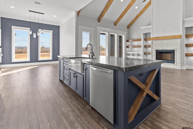 kitchen with sink, hanging light fixtures, dishwasher, an island with sink, and a fireplace