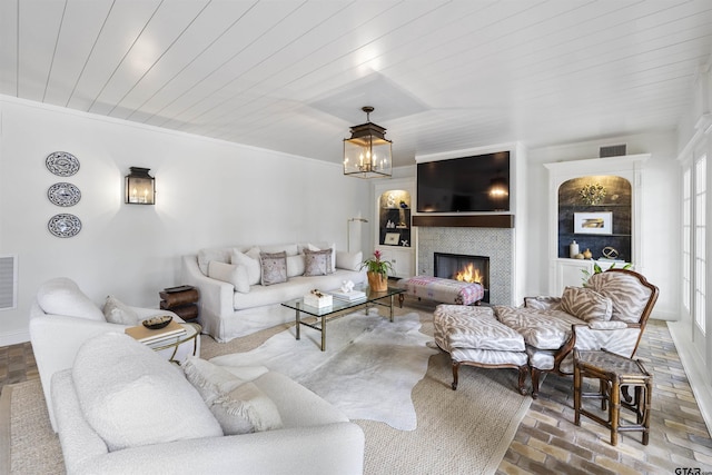 2417 Old Bullard Rd, Tyler, TX 75701 - living area featuring a warm lit fireplace, a chandelier, brick floors, and wood ceiling