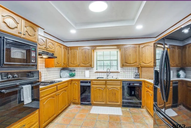 kitchen with a tray ceiling, sink, decorative backsplash, and black appliances