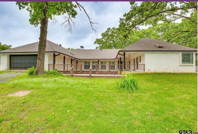 back of property featuring a yard, a garage, and a wooden deck