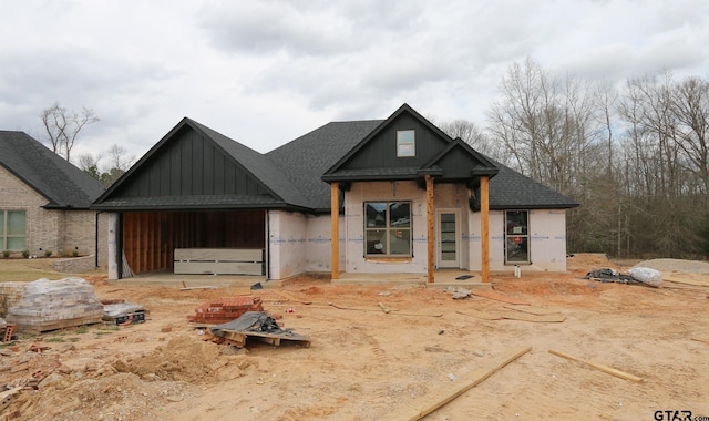 unfinished property with board and batten siding and roof with shingles