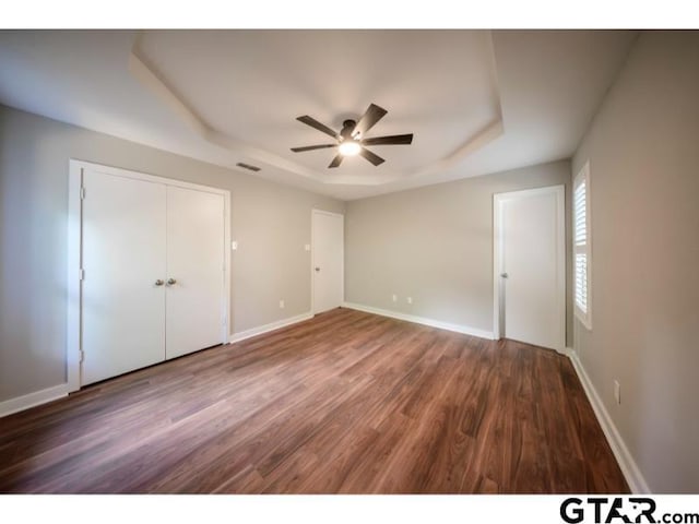 411 Lakeview St, Whitehouse, TX 75791 - unfurnished bedroom with a tray ceiling, wood finished floors, a closet, and a ceiling fan