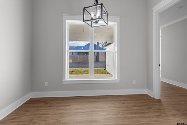 unfurnished dining area with hardwood / wood-style floors, a healthy amount of sunlight, and a chandelier