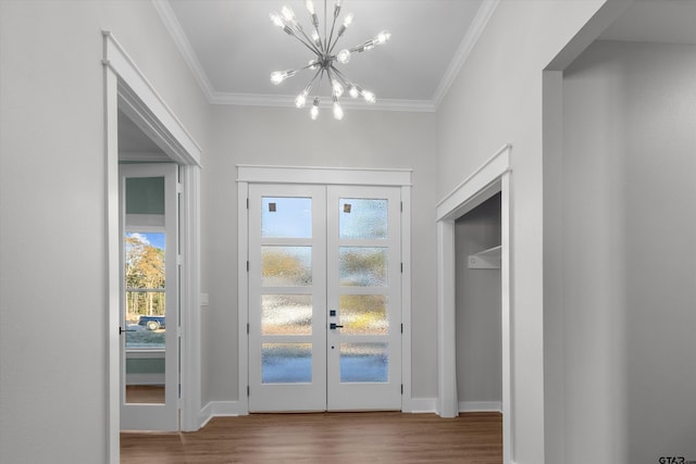 entryway with hardwood / wood-style flooring, a chandelier, ornamental molding, and french doors