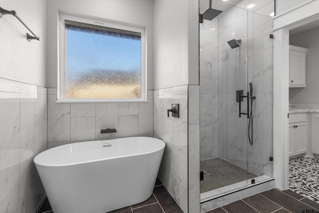 bathroom with tile patterned flooring, tile walls, and independent shower and bath