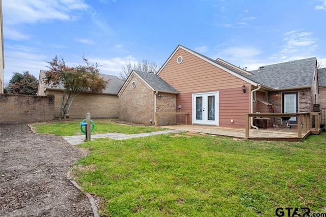 back of property featuring brick siding, a yard, a deck, and french doors