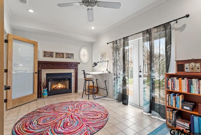 sitting room with ornamental molding, a warm lit fireplace, french doors, and light tile patterned flooring