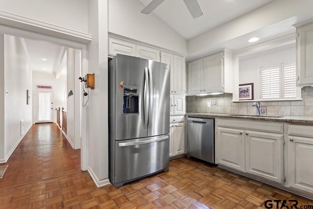 kitchen with appliances with stainless steel finishes, a sink, white cabinetry, and tasteful backsplash